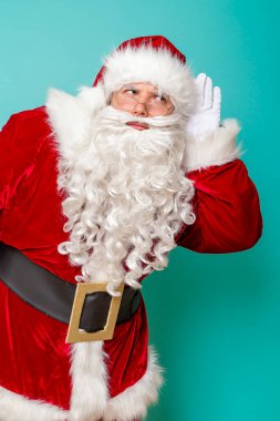 Noel Baba 'nın portresi kulağının yanında duruyor, çocukların noel hediyesi dileklerini dinliyor, renkli arka planda izole edilmiş.