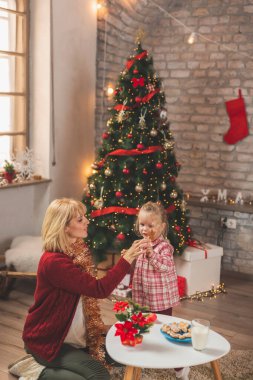 Güzel anne ve kız Noel 'i evde kutlarken, zencefilli kek yerken ve süt içerken eğleniyorlar.