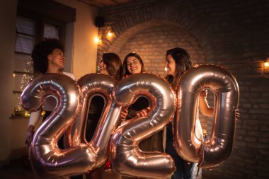 Yeni yıl arifesini birlikte kutlayan bir grup kadın, 2020 numaralı dev balonları ellerinde tutarak yaklaşan yeni yılı temsil ediyorlar.