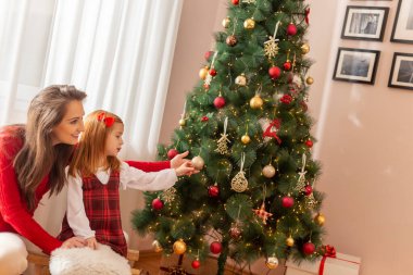 Güzel anne ve kız, köy kızağında oturup Noel 'i evde geçirirken eğleniyorlar, Noel ağacını süslüyorlar.