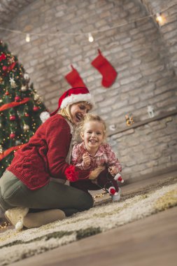 Anne ve kız Noel 'i evde kutlarken eğleniyorlar. Güzel dekore edilmiş bir Noel ağacının yanında sarılıyorlar, gıdıklıyorlar ve gülüyorlar.