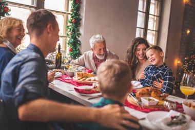 Güzel mutlu aile masanın etrafında toplanmış, Noel yemeği yiyor, birlikte vakit geçiriyorlar ve kış tatili sezonunun tadını çıkarıyorlar.