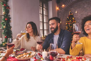Arkadaşlar Noel 'i kutlarken, masada otururken, şarap içerken ve kış tatillerinde birlikte vakit geçirirken eğleniyorlar.