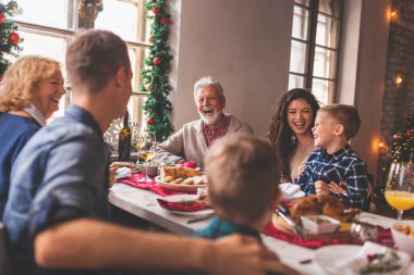 Güzel mutlu aile masanın etrafında toplanmış, Noel yemeği yiyor, kış tatilinin tadını çıkarıyor ve birlikte vakit geçiriyorlar.
