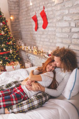 Birbirine aşık genç bir çift Noel sabahı yatakta pijama giyer, kış tatilinde evde sarılır ve dinlenir.