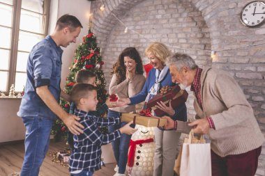 Mutlu aile güzelce dekore edilmiş Noel ağacının etrafında toplanmış Noel 'i evde kutluyor, hediyeleri değiş tokuş ediyor ve açıyor.