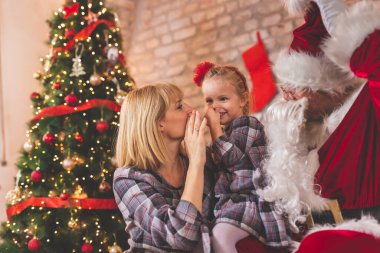 Anne ve kızı Noel 'i evde kutlarken, Noel Baba kılığında babalarıyla oynarken; aileler Noel için çocuklarını şaşırtıyor.