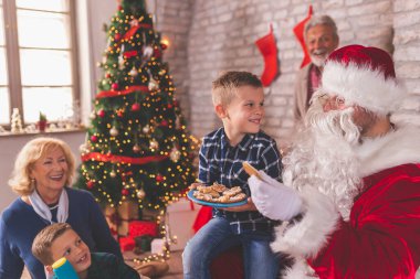 Çocuklar Noel 'i Noel Baba' ya hediyeler aldıktan sonra Noel Baba 'ya zencefilli kurabiye ikram ederek evde dedeleriyle geçiriyorlar.
