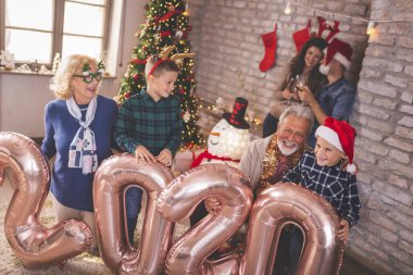 Güzel mutlu bir aile Noel 'i evde kutluyor, 2020 numaralı dev balonları tutarak eğleniyor, gelecek yeni yılı temsil ediyor.