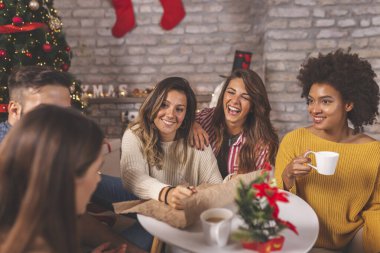 Bir grup arkadaş güzelce dekore edilmiş Noel ağacının yanında oturmuş, yeni yıl kararlarını yazarken eğleniyorlar.