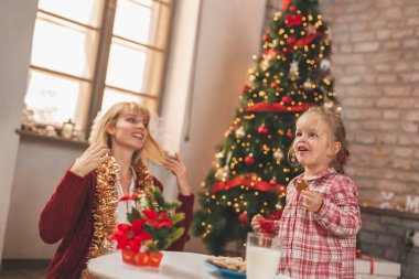 Güzel bekar anne Noel 'i küçük kızıyla birlikte kutlarken, zencefilli Noel kurabiyesi yerken ve süt içerken eğleniyor.