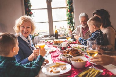 Mutlu bir aile Noel 'i kutluyor, evde yemek yiyor, bir kadeh şarap ve portakal suyuyla kadeh kaldırıyor ve birlikte vakit geçiriyorlar.