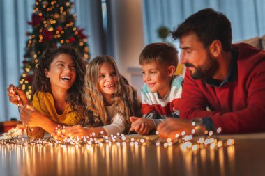 Güzel, mutlu bir aile Noel 'i evde kutluyor, aileler ve çocuklar Noel ağacının yanında yerde yatıyor.