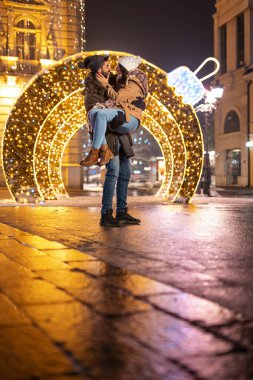 Güzel, genç ve aşık bir çift kış tatili sezonunda şehir sokaklarında vakit geçiriyorlar. Erkek arkadaşı, arka planda Noel ışıklarıyla kız arkadaşını kucağında taşıyor.