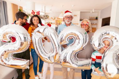Aileler, çocuklar ve torunlar Noel 'i evde kutluyor, 2022 numaralı dev balonları tutarak eğleniyorlar, gelecek yeni yılı temsil ediyorlar.