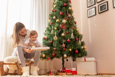 Anne ve küçük tatlı çocuk Noel günü evde eğleniyor, Noel ağacı süslüyorlar.