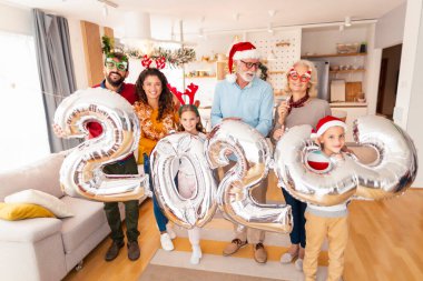 Güzel mutlu bir aile Noel 'i evde kutluyor, 2023 numaralı dev balonları tutarak eğleniyor, gelecek yeni yılı temsil ediyor.