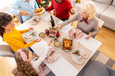 Masanın etrafına toplanmış güzel, mutlu bir aile manzarası, evde hep birlikte Noel yemeği yemek, tabakları birbirine vermek, konuşmak ve gülmek.