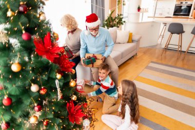 Noel 'i evde birlikte kutlayan aile, Noel günü torunlarına hediye veren büyükanne ve büyükbaba.