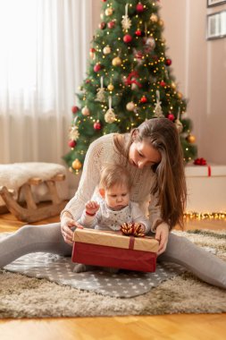 Anne ve oğlu Noel sabahı evde eğleniyor, güzelce süslenmiş Noel ağacının yanında oturuyor, hediyeleri açıyor ve oyun oynuyorlar.