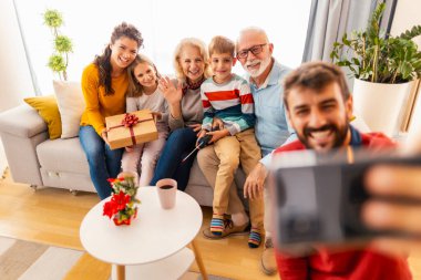 Mutlu çok nesilli aile evde birlikte Noel 'i kutlarken selfie çekerken eğleniyor.