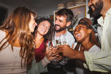 Bir grup genç arkadaş şarkı söylüyor, dans ediyor ve kadeh kaldırıyor. Yılbaşı partisinde şampanya kadehlerini kaldırıyorlar.