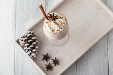 Tarçınlı bardakta servis edilen nefis ev yapımı kremalı yumurta likörü tablosu. Anason yıldızı ve tarçın çubuklarıyla süslenmiş. Geleneksel kış tatili kokteyli.