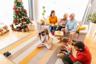 Mutlu çoklu nesil aile Noel için evde toplandı, Noel 'i evde kutluyor, çocuklar hediyeleri açıyor ve yeni oyuncaklarla oynuyorlar.