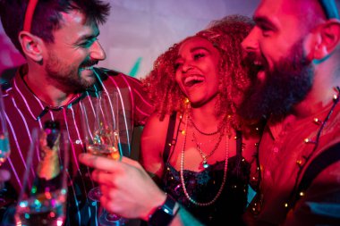 Bir grup neşeli genç arkadaş gece yarısı partisinde dans edip şampanya içerek eğleniyor.