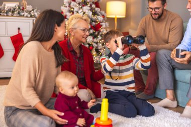 Mutlu çok nesilli aileler Noel 'i evde birlikte geçiriyorlar, çocuklar hediye olarak aldıkları oyuncaklarla oynuyorlar.