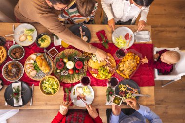 Masanın etrafında toplanmış mutlu, mutlu, çok nesilli aile manzarası, evde hep birlikte Noel yemeği yiyor, birbiriyle konuşuyor ve gülüyor.