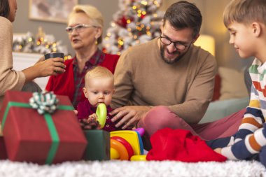 Mutlu çok nesilli aile Noel 'i evde birlikte geçiriyorlar, baba hediyeleri açıyor ve çocuklarla oynuyor.