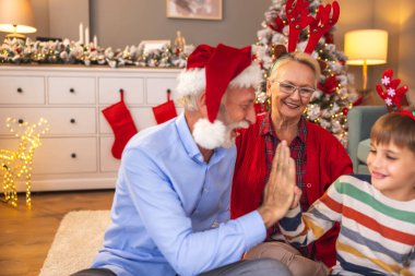 Büyükannem ve büyükbabam Noel günü torunumla evde oynarken, büyükbabam torunumla beşlik çakarken eğleniyordu.