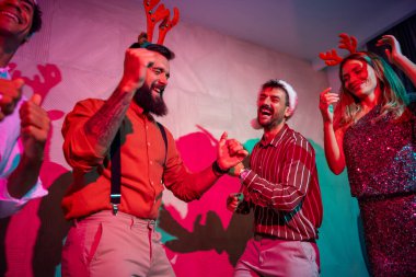 Bir grup neşeli genç arkadaş yeni yıl partisinde dans edip şarkı söylüyor.