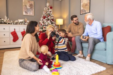 Mutlu çok nesilli aileler Noel 'i evde birlikte geçiriyorlar, çocuklar hediye olarak aldıkları oyuncaklarla oynuyorlar.