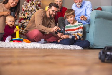 Mutlu çok nesilli aileler Noel 'i evde birlikte geçiriyorlar. Çocuklar Noel hediyesi olarak aldıkları oyuncaklarla oynuyorlar.