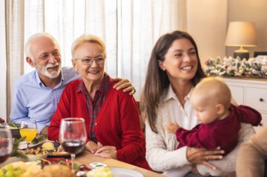 Mutlu çok nesilli aile, Noel yemeğini evde yemek ve kış tatilini birlikte geçirmek için masanın etrafında toplandı.