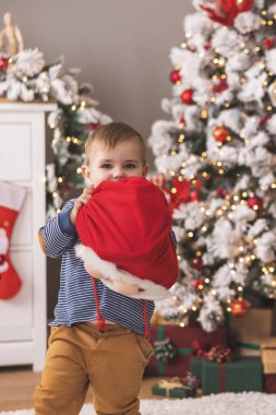 Küçük tatlı çocuk Noel 'i evde ailesiyle, elinde Noel hediyeleriyle geçirirken eğleniyor.