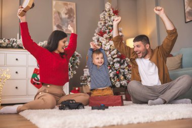 Genç ebeveynler Noel 'i evde yeni yürümeye başlayan çocuklarıyla birlikte geçiriyorlar, hediyeleri açıyorlar ve yeni oyuncaklarla oynuyorlar.