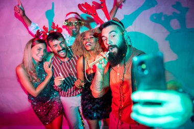 Bir grup neşeli genç arkadaş yeni yıl partisinde selfie çekerken eğleniyorlar.