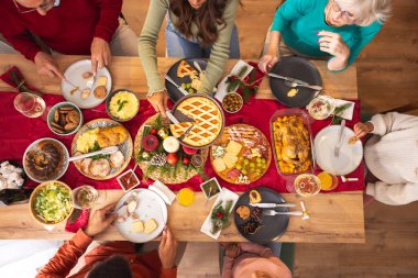 Masanın etrafında toplanmış mutlu, mutlu, çok nesilli aile manzarası, evde hep birlikte Noel yemeği yiyor, birbiriyle konuşuyor ve gülüyor.