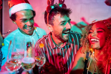 Bir grup neşeli genç arkadaş gece yarısı partisinde dans edip şampanya içerek eğleniyor.