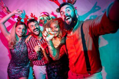 Bir grup neşeli genç arkadaş yeni yıl partisinde selfie çekerken eğleniyorlar.