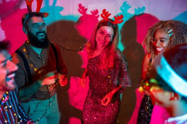 Bir grup neşeli genç arkadaş yeni yıl partisinde şarkı söyleyip dans ediyor.