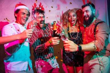 Bir grup neşeli genç arkadaş yılbaşı partisinde şampanya açıp dans ederek eğleniyor.