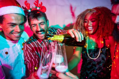 Bir grup neşeli genç arkadaş, gece yarısı partisinde şampanya doldurup dans ederek eğleniyor.