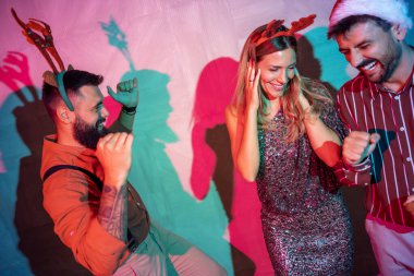 Bir grup neşeli genç arkadaş yeni yıl partisinde dans edip şarkı söylüyor.