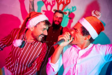 Bir grup neşeli erkek arkadaş yeni yıl partisinde karaoke söyleyip dans ederek eğleniyor.