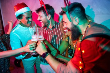 Bir grup neşeli genç arkadaş kadeh kaldırarak eğleniyor ve yılbaşı partisinde şampanya içiyorlar.