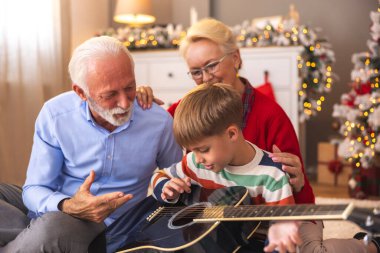 Küçük çocuk kış tatilini büyükannesi ve büyükbabasıyla geçiriyor. Büyükbabası da torununa Noel 'de evde gitar çalmayı öğretiyor.